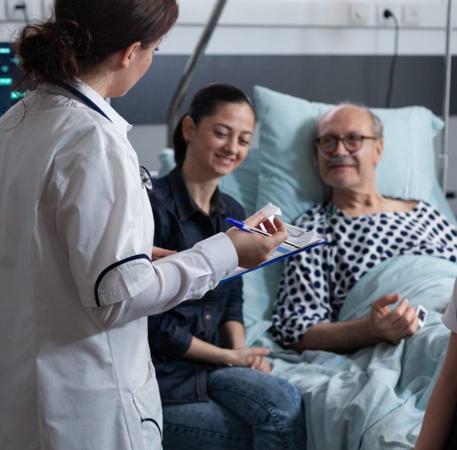 Elderly people care nurse reviewing files of senior male patient bedridden in geriatric hospital. Female general practitioner listening to older hospitalized man symptoms.
